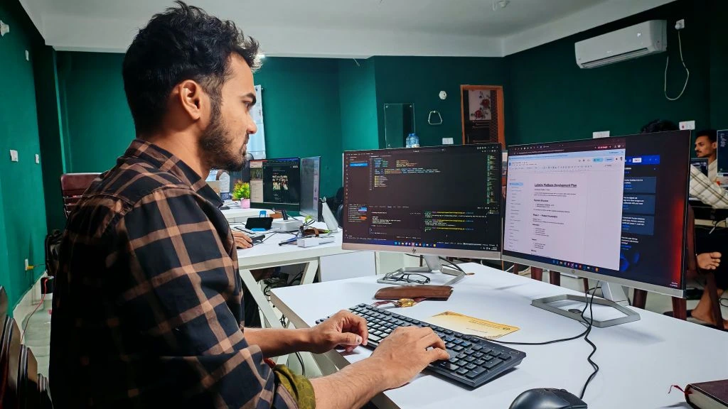 Hands typing on a laptop in a co-working space